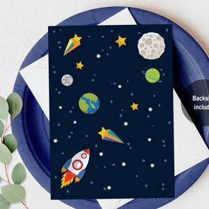 Puede incluir: Una tarjeta azul oscuro con tem&aacute;tica espacial. La tarjeta presenta un cohete, estrellas, planetas y un cometa. El texto "Backside included" est&aacute; impreso en la tarjeta.