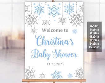 Puede incluir: Un cartel blanco para baby shower con copos de nieve azules y copos de nieve plateados con purpurina. El cartel dice "Bienvenido a la fiesta de bienvenida de Christina" y la fecha "11.20.2025". El cartel está disponible en los tamaños 8x10in, 11x14in, 16x20in, 18x24in, 20x30in y 24x36in.