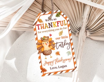 Könnte beinhalten: Ein Thanksgiving-Geschenk-Etikett mit einer Cartoon-Truthahn-Illustration. Das Etikett hat einen rot-weiß-braunen gestreiften Hintergrund mit dem Text "We're so THANKFUL for everything you do for our little turkey Happy Thanksgiving! Love, Logan".