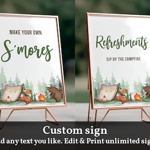 May include: Two printable signs with a woodland theme. The first sign says "Make Your Own S'mores" and the second sign says "Refreshments Sip by the Campfire". Both signs feature a campfire scene with a tent, animals, and trees.