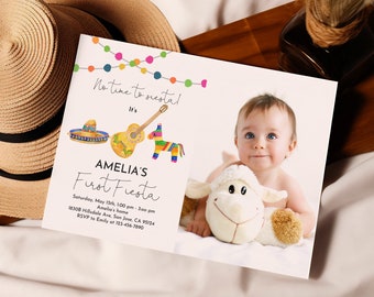 May include: A white invitation card with colorful string lights at the top. The text reads "No time to siestal It's Amelia's First Fiesta" with a sombrero, guitar, and a pinata. The invitation includes the date, time, location, and RSVP information. A photo of a baby holding a stuffed lamb is in the bottom right corner.