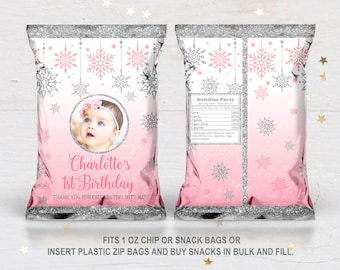 May include: Pink and silver snowflake-themed party favor bags with a photo of a baby girl and the text "Charlotte's 1st Birthday". The bags are designed to fit 1 ounce chip or snack bags.