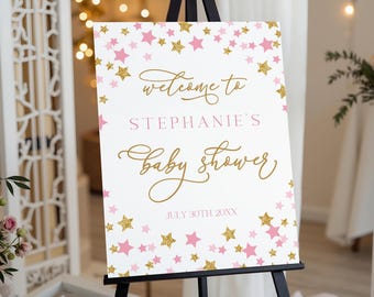 Może przedstawiać: Biały szyld na baby shower na czarnym sztaludze. Znak zawiera różowe i złote gwiazdki z napisem "welcome to STEPHANIE'S baby shower" złotym skryptem i różowymi literami blokowymi. Data "JULY 30TH, 20XX" jest również uwzględniona.