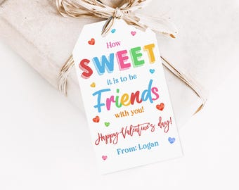 May include: A white gift tag with colourful text that reads "How SWEET it is to be Friends with you! Happy Valentine's Day! From: Logan". The tag is decorated with small pink, blue, yellow, and orange hearts.