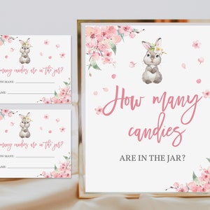 Op de afbeelding: Een printbare spelkaart met een roze bloemenontwerp en een schattig konijn. De kaart vraagt ​​"Hoeveel snoepjes zitten er in de pot?" en heeft regels voor gasten om hun schattingen en namen in te vullen.