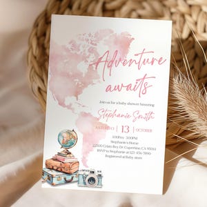 Puede incluir: Invitación a un baby shower con un mapa del mundo en acuarela rosa y las palabras "Adventure awaits". La invitación incluye un globo terráqueo, libros apilados, maletas vintage y una cámara. El texto dice "Join us for a baby shower honoring Stephanie Smith."