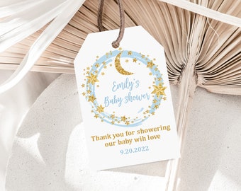 May include: A white tag with blue and gold glitter accents. The tag features a crescent moon and stars in a circle with the text "Emily's Baby Shower" and "Thank you for showering our baby with love 9.20.2022".