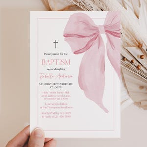 May include: A baptism invitation with a watercolor pink bow and text. The invitation includes the text "Please join us for the BAPTISM of our daughter Isabelle Anderson" and event details. The invitation is on a white background.