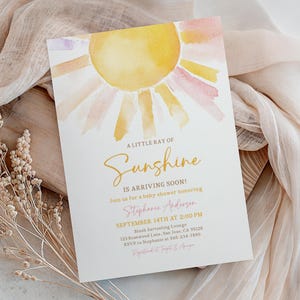 May include: A rectangular baby shower invitation card featuring a watercolor sun illustration in yellow and pink hues. The text reads: A LITTLE RAY OF Sunshine IS ARRIVING SOON! Join us for a baby shower honoring Stephanie Anderson, SEPTEMBER 14TH AT 2:00 PM, Blush Dartealing Lounge, 123 Rosewood Lane, San Jose, CA 95128, RSVP to Stephanie at 565-234-7890, Registered at Target & Amazon.