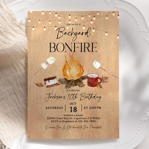 Puede incluir: Una invitaci&oacute;n r&uacute;stica para una fogata en el patio trasero, con una ilustraci&oacute;n en acuarela de una fogata, malvaviscos y s'mores. El texto dice "Backyard Bonfire" y anuncia el d&eacute;cimo cumplea&ntilde;os de Jackson el 18 de octubre a las 2:00 PM.