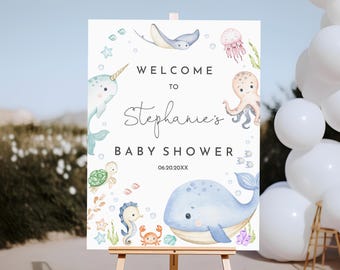 May include: Welcome to Stephanie's Baby Shower sign with a watercolor design featuring a narwhal, whale, octopus, seahorse, turtle, and jellyfish. The sign is on a wooden easel.