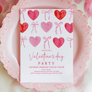 Puede incluir: Una invitaci&oacute;n a una fiesta de San Valent&iacute;n en un plato rosa. La invitaci&oacute;n presenta corazones y lazos de acuarela, con el texto "Join us for a Valentine's Day Party" y detalles del evento. El plato tiene un borde festoneado.