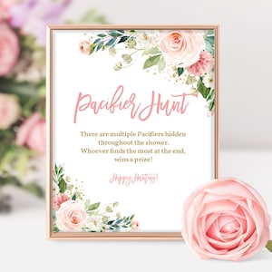 May include: A pink and gold printable sign with floral accents that reads "Pacifier Hunt". The sign says "There are multiple Pacifiers hidden throughout the shower. Whoever finds the most at the end, wins a prize! Happy Hunting!"