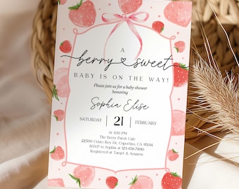 May include: A rectangular baby shower invitation card featuring a watercolor strawberry pattern on a light pink background. The center includes a pink frame with a bow and the text: A berry sweet baby is on the way! Honoring Sophia Elise, Saturday 21 February.