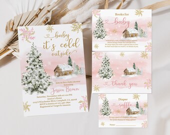 Op de afbeelding: Roze en gouden babyborrel uitnodiging met een winterthema. De uitnodiging toont een besneeuwde hut, dennenbomen en sneeuwvlokken. De tekst luidt "baby it's cold outside".