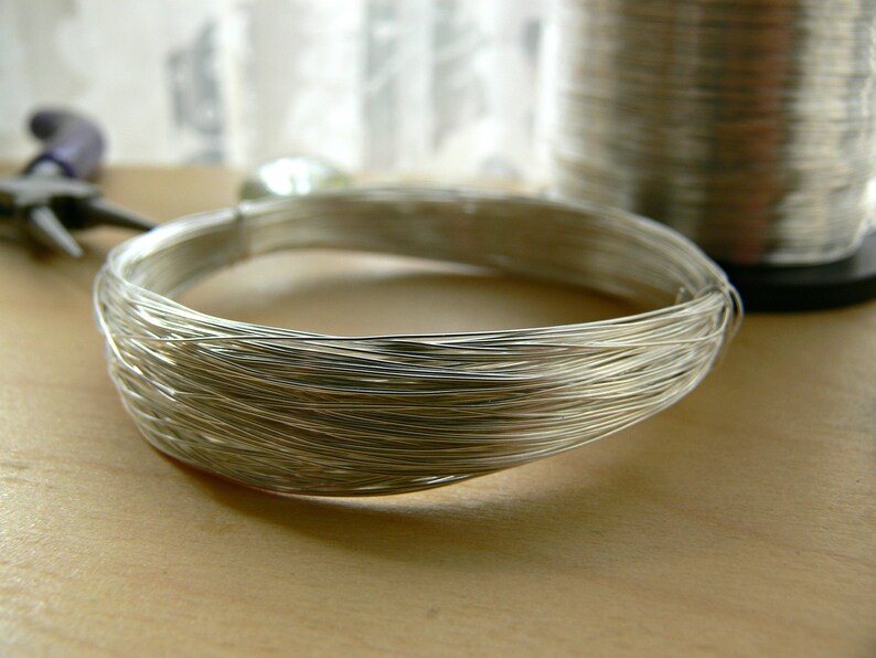 May include: A close-up of a silver wire coil, likely used for jewelry making or crafting.