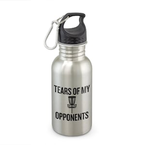 May include: A silver stainless steel water bottle with a black lid and a carabiner clip. The bottle has a black graphic that says "Tears of My Opponents" with a disc golf basket.