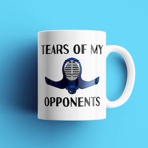 May include: White ceramic mug with a black and blue illustration of a fencing mask and the text "Tears of my opponents".