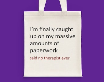 May include: White tote bag with the text "I'm finally caught up on my massive amounts of paperwork said no therapist ever" printed in black.