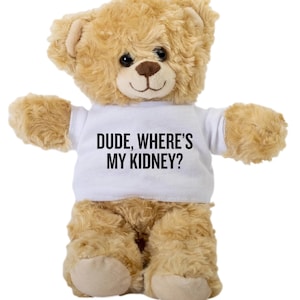 Puede incluir: Un oso de peluche marrón que lleva una camiseta blanca con el texto "DUDE, WHERE'S MY KIDNEY?" impreso en negro.