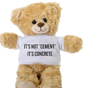 Op de afbeelding: Een bruine teddybeer die een wit T-shirt draagt met de tekst "It's not "cement" It's concrete" erop gedrukt.
