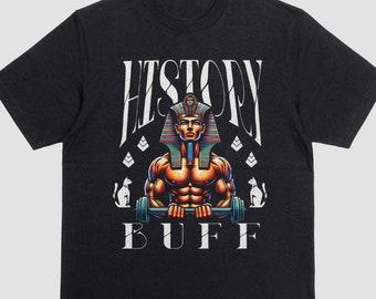 Puede incluir: Camiseta negra con un estampado gráfico de un hombre musculoso con un tocado de faraón y levantando una barra. El texto "HISTORY BUFF" está impreso debajo de la imagen.
