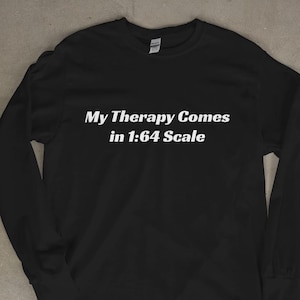 Può includere: Maglietta nera a maniche lunghe con il testo bianco "My Therapy Comes in 1:64 Scale". La maglietta ha un girocollo e maniche lunghe. L'indumento è realizzato in un materiale morbido.
