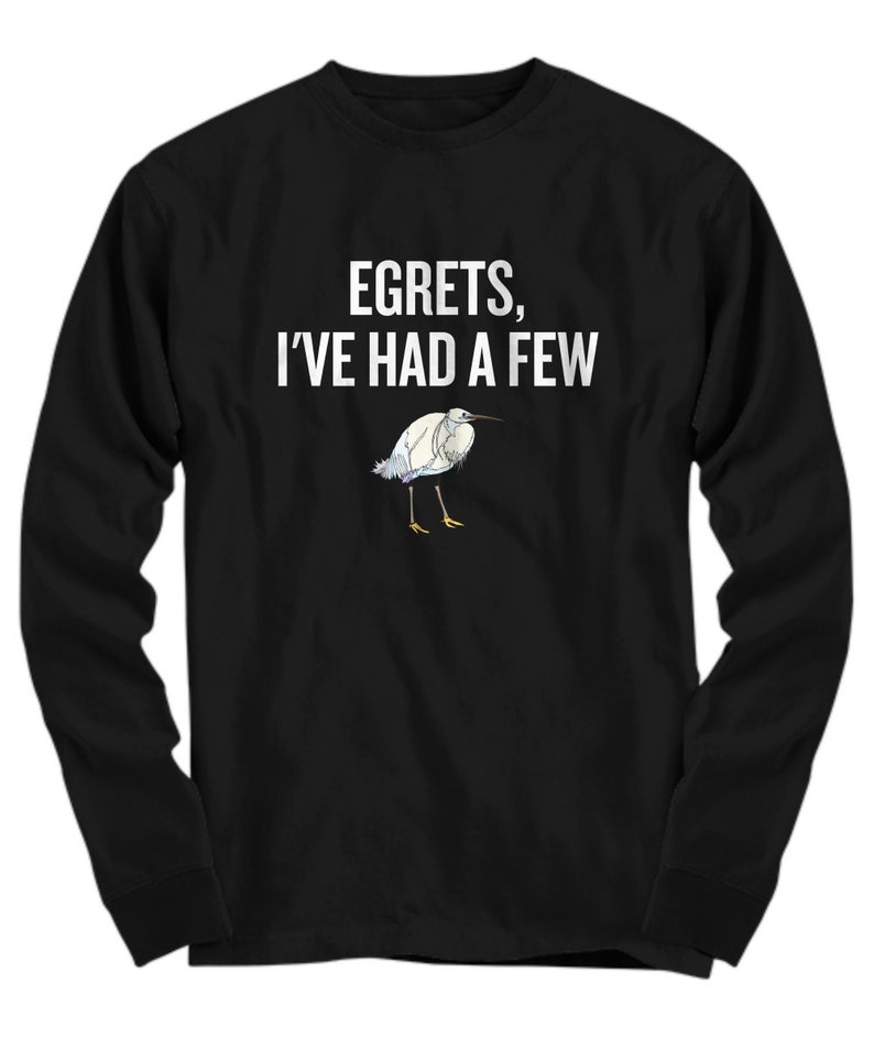 May include: Black long-sleeve shirt with the text "EGRETS, I'VE HAD A FEW" in white. Below the text is a watercolor illustration of a white egret with blue and yellow accents. The shirt is made of a soft material.