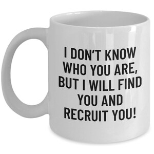 May include: White ceramic mug with a curved handle. The mug features black text that reads: "I DON'T KNOW WHO YOU ARE, BUT I WILL FIND YOU AND RECRUIT YOU!" A humorous and motivational gift for recruiters or HR professionals.