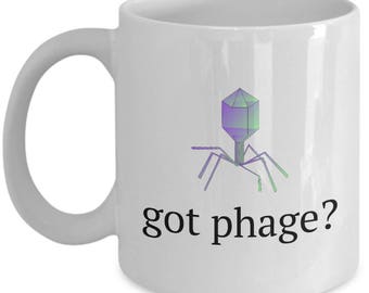 Puede incluir: Taza de café de cerámica blanca con un gráfico de un bacteriófago, un virus que infecta bacterias. El texto "got phage?" está impreso debajo del gráfico.