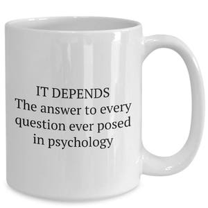 May include: White ceramic coffee mug with black text that reads "IT DEPENDS The answer to every question ever posed in psychology"