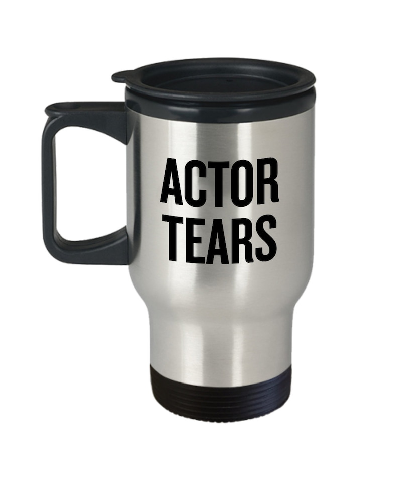May include: A silver travel mug with a black lid and handle. The mug has the text "ACTOR TEARS" printed in black on the front.
