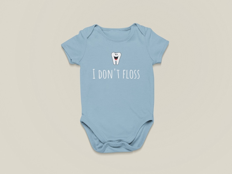 Peut inclure: Une grenouill&egrave;re b&eacute;b&eacute; bleu clair avec une dent de dessin anim&eacute; blanche et le texte "Je ne passe pas de fil dentaire".