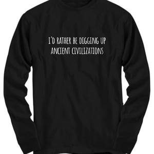 May include: Black long-sleeved shirt with white text that reads "I'd rather be digging up ancient civilizations".