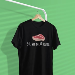 May include: Black t-shirt with a white graphic of a steak and the text "SO, WE MEAT AGAIN."