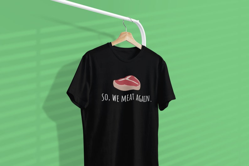 May include: Black t-shirt with a white graphic of a steak and the text "SO, WE MEAT AGAIN."