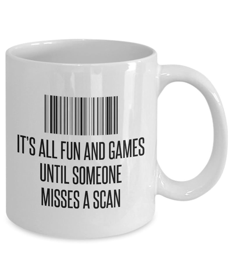 May include: White ceramic mug with a black barcode design and the text "IT'S ALL FUN AND GAMES UNTIL SOMEONE MISSES A SCAN". The mug has a curved handle and is suitable for hot or cold beverages.