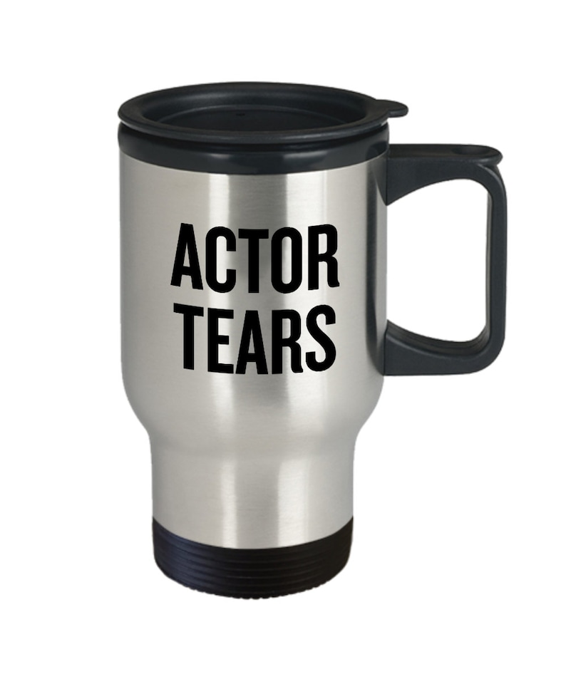 May include: A silver travel mug with a black lid and handle. The mug has the text "ACTOR TEARS" printed on it in black.