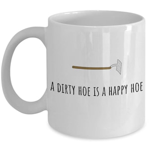May include: White ceramic coffee mug with a black and brown illustration of a garden hoe and the text "A dirty hoe is a happy hoe".