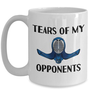 May include: White ceramic coffee mug with a black and blue illustration of a kendo helmet and the text "Tears of my opponents".