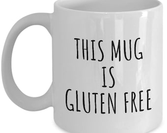 May include: White ceramic coffee mug with black text that reads "This mug is gluten free".