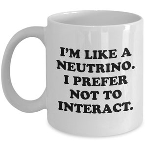 Könnte beinhalten: Weißer Keramikbecher mit gebogenem Henkel. Der Becher trägt den Text "I'M LIKE A NEUTRINO. I PREFER NOT TO INTERACT." in fetten schwarzen Buchstaben. Für Heißgetränke.