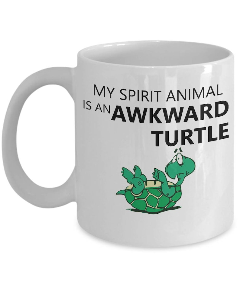 Może przedstawiać: Biały ceramiczny kubek do kawy z czarno-zielonym rysunkiem ż&oacute;łwia na plecach. Tekst na kubku brzmi "My spirit animal is an awkward turtle."