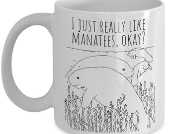 May include: White ceramic coffee mug with a black line drawing of manatees and the text "I just really like manatees, okay?"