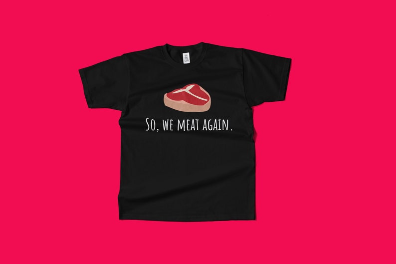 May include: Black t-shirt with a white graphic of a steak and the text "So, we meat again."