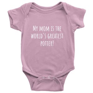 Op de afbeelding: Een roze baby romper met de tekst "My Mom is the World's Greatest Potter!" in wit.