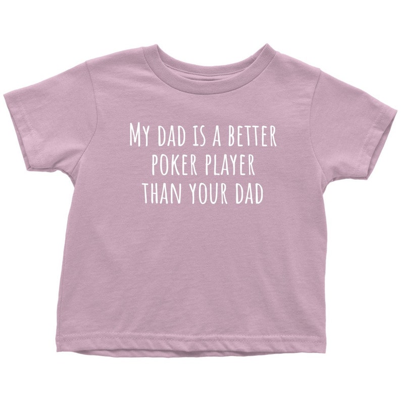 May include: A light purple t-shirt with the text "My dad is a better poker player than your dad" printed in white.