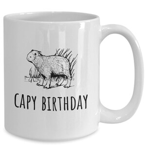 May include: White ceramic coffee mug with a black line drawing of a capybara and the text "CAPY BIRTHDAY".