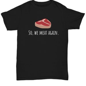 May include: Black t-shirt with a white graphic of a steak and the text "So, we meat again."
