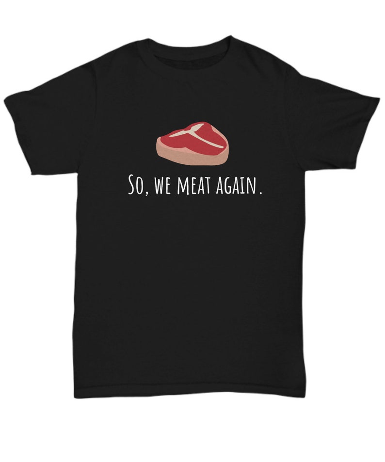 May include: Black t-shirt with a white graphic of a steak and the text "So, we meat again."